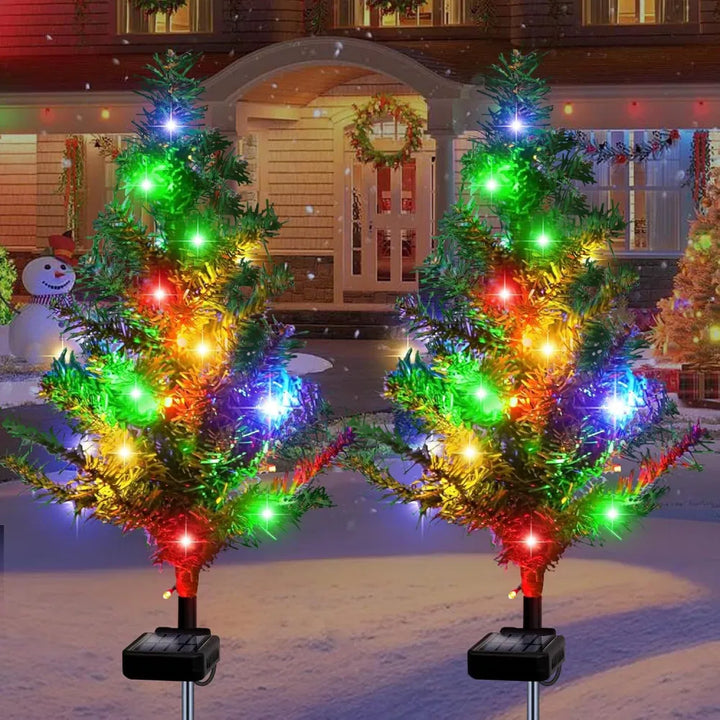 Four solar mini Christmas trees glowing along a path