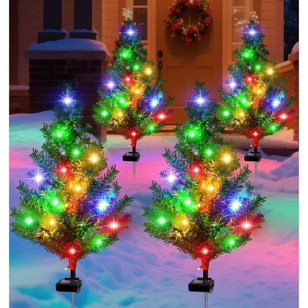 Four solar mini Christmas trees glowing along a path