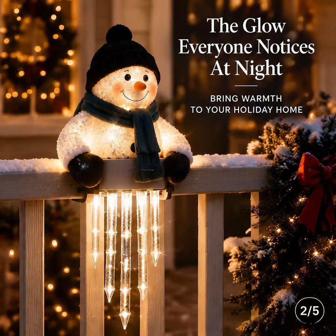 Lit snowman figure sitting on a ledge with hanging icicles