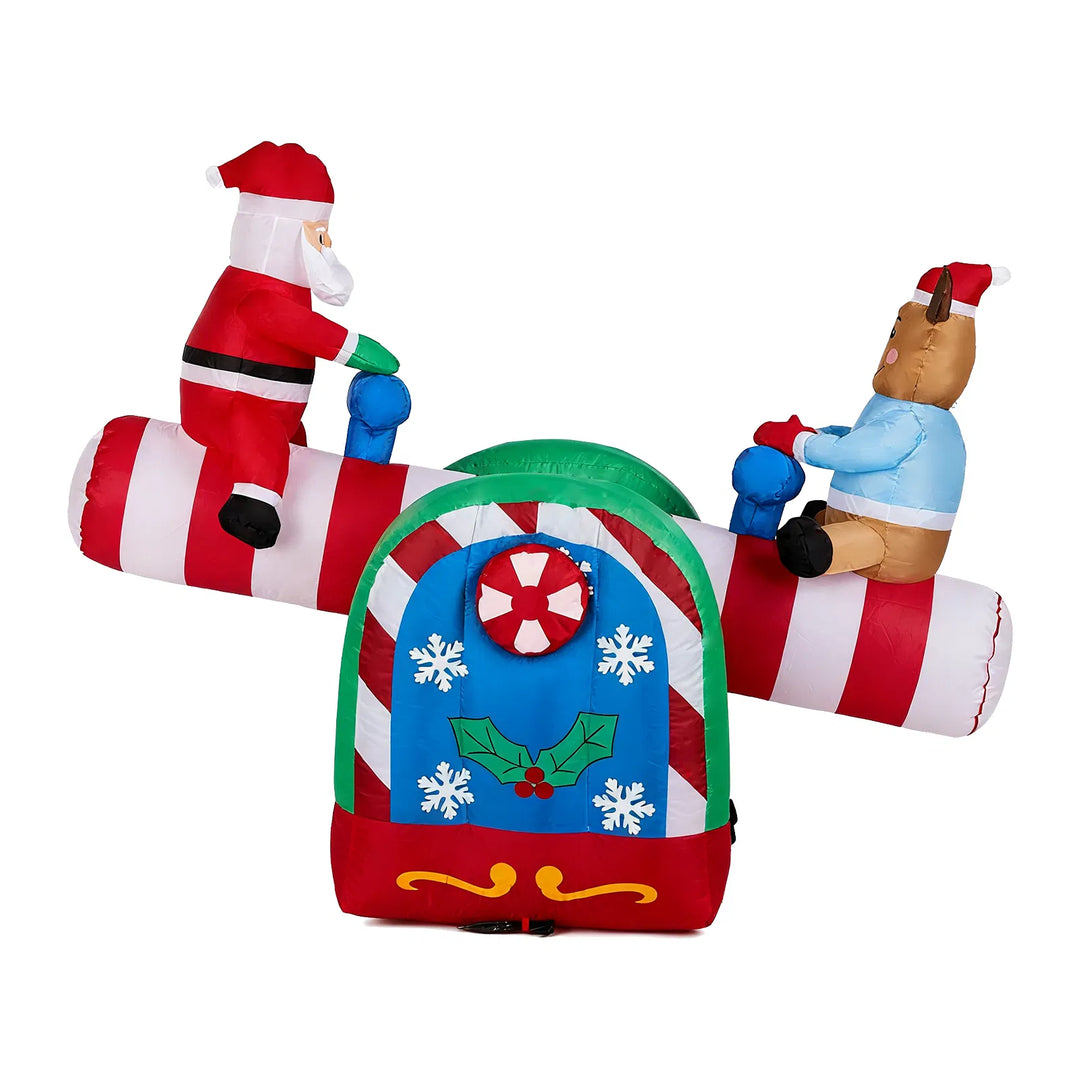 Inflatable Santa and reindeer seesaw lit at night