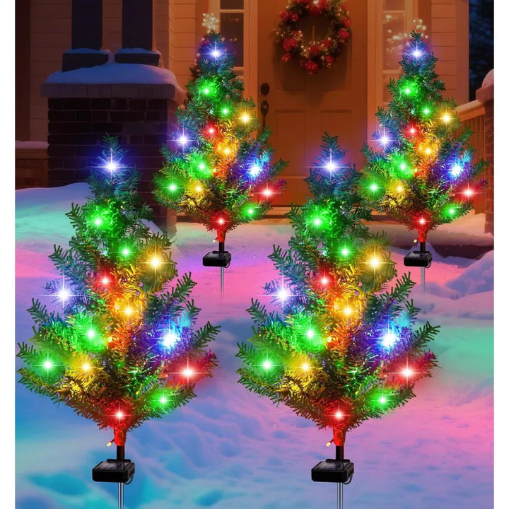 Four solar mini Christmas trees glowing along a path