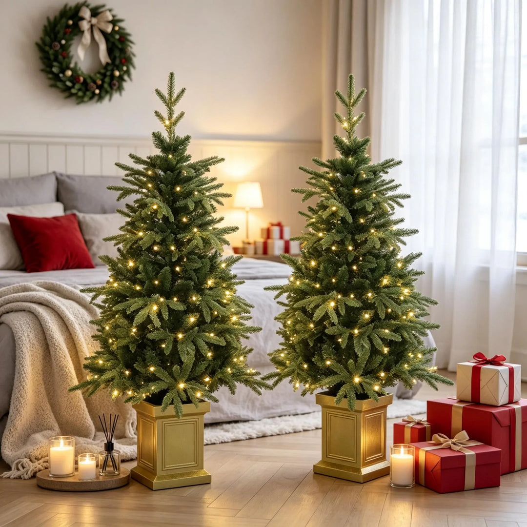Two potted lit Christmas trees in gold pots
